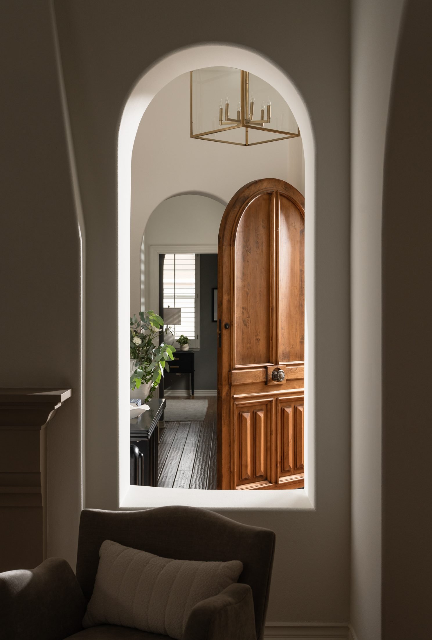 Arched hallway with a wood door, interior design by S & S Interiors