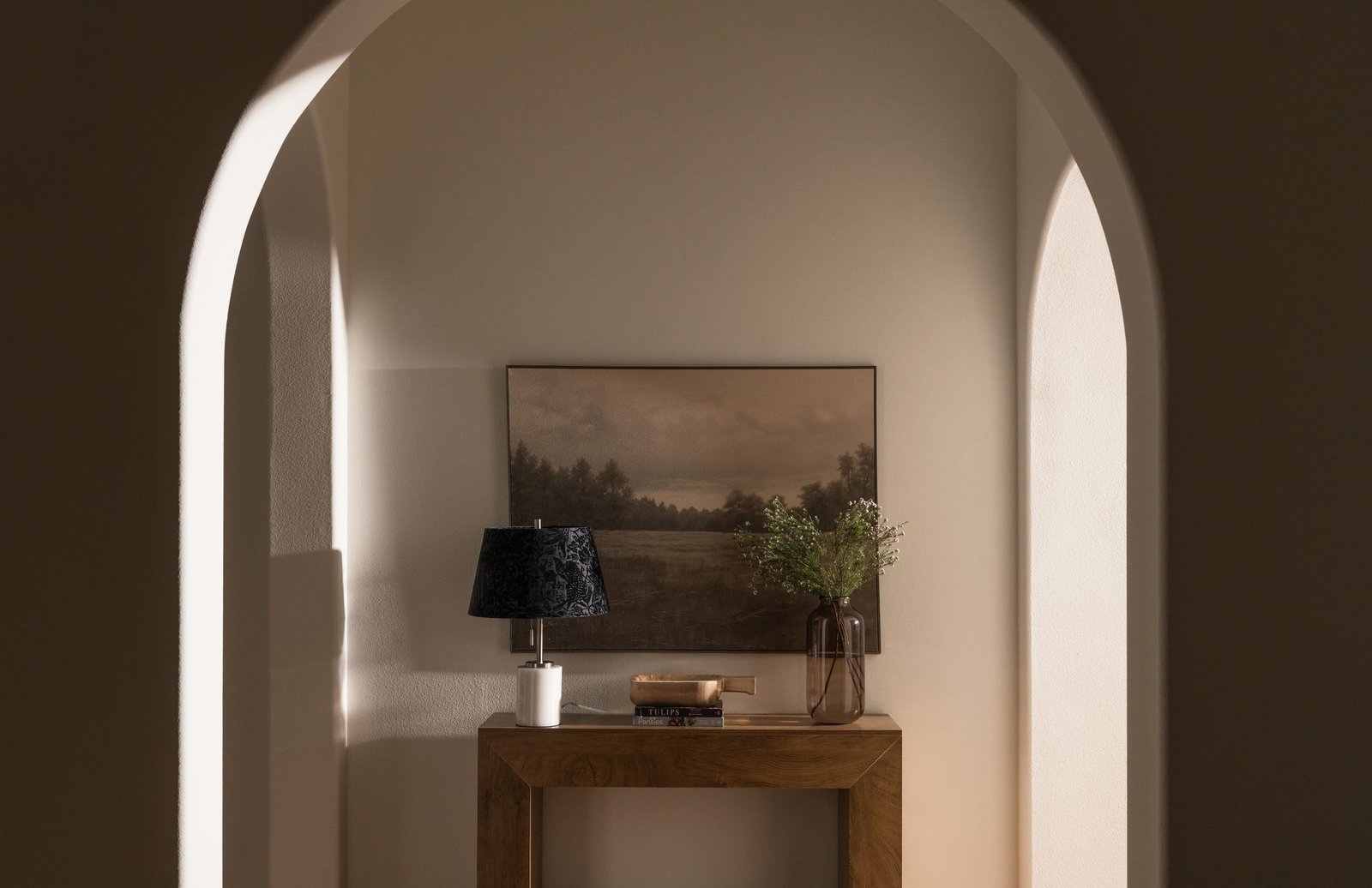 Arched niche with a console and landscape art