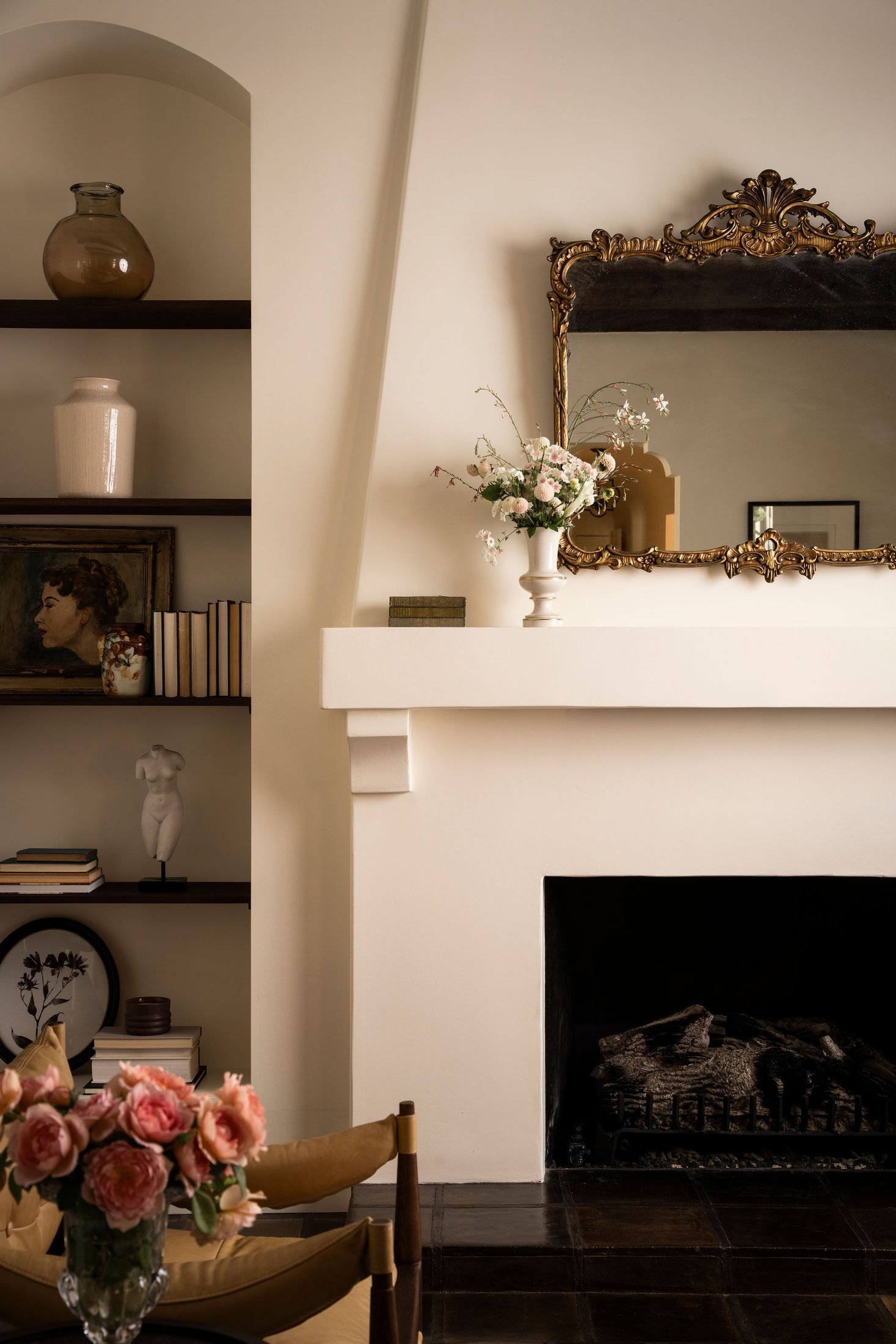 Detail of a styled fireplace vignette with fresh flowers