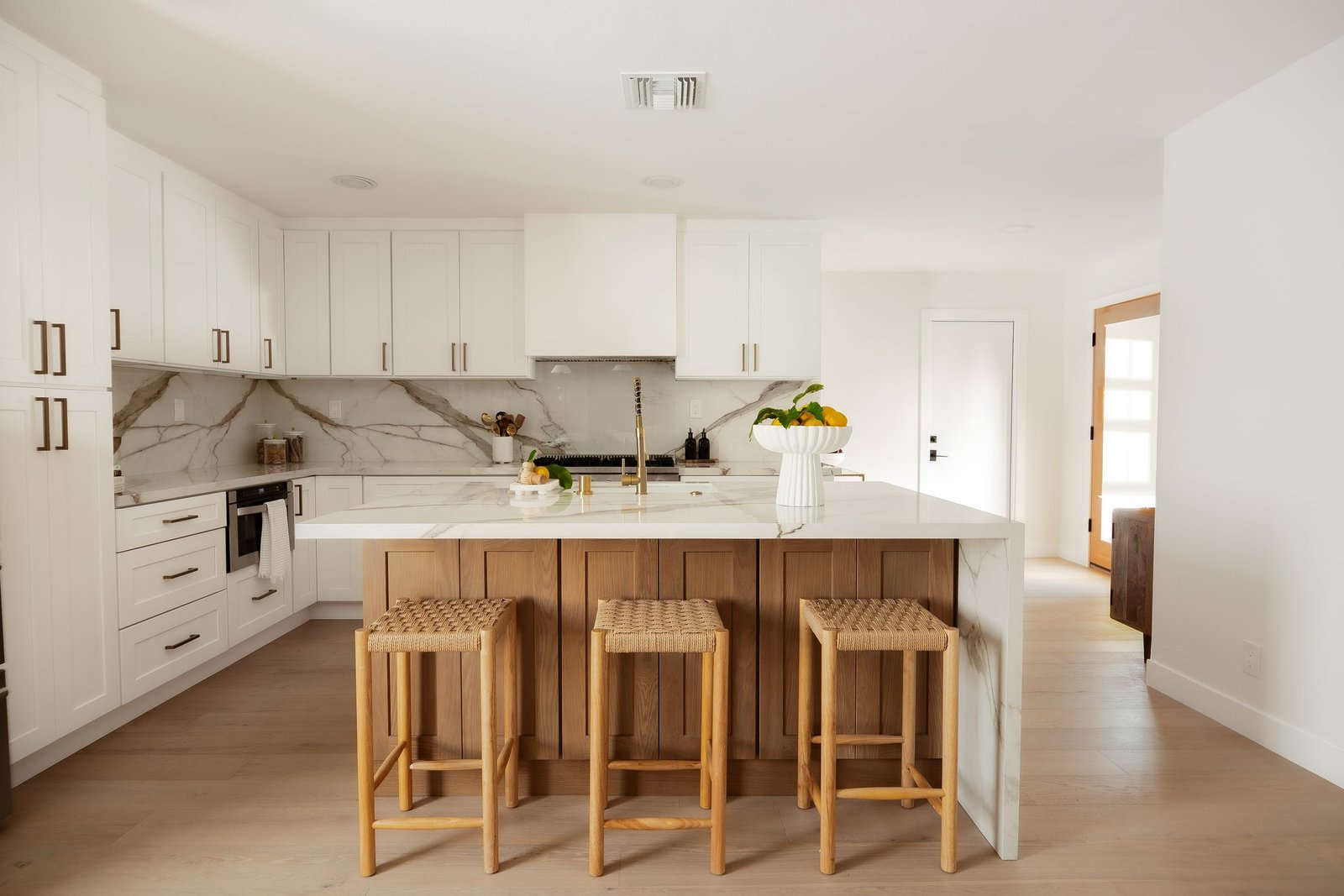 White kitchen with wood bar stools and an island