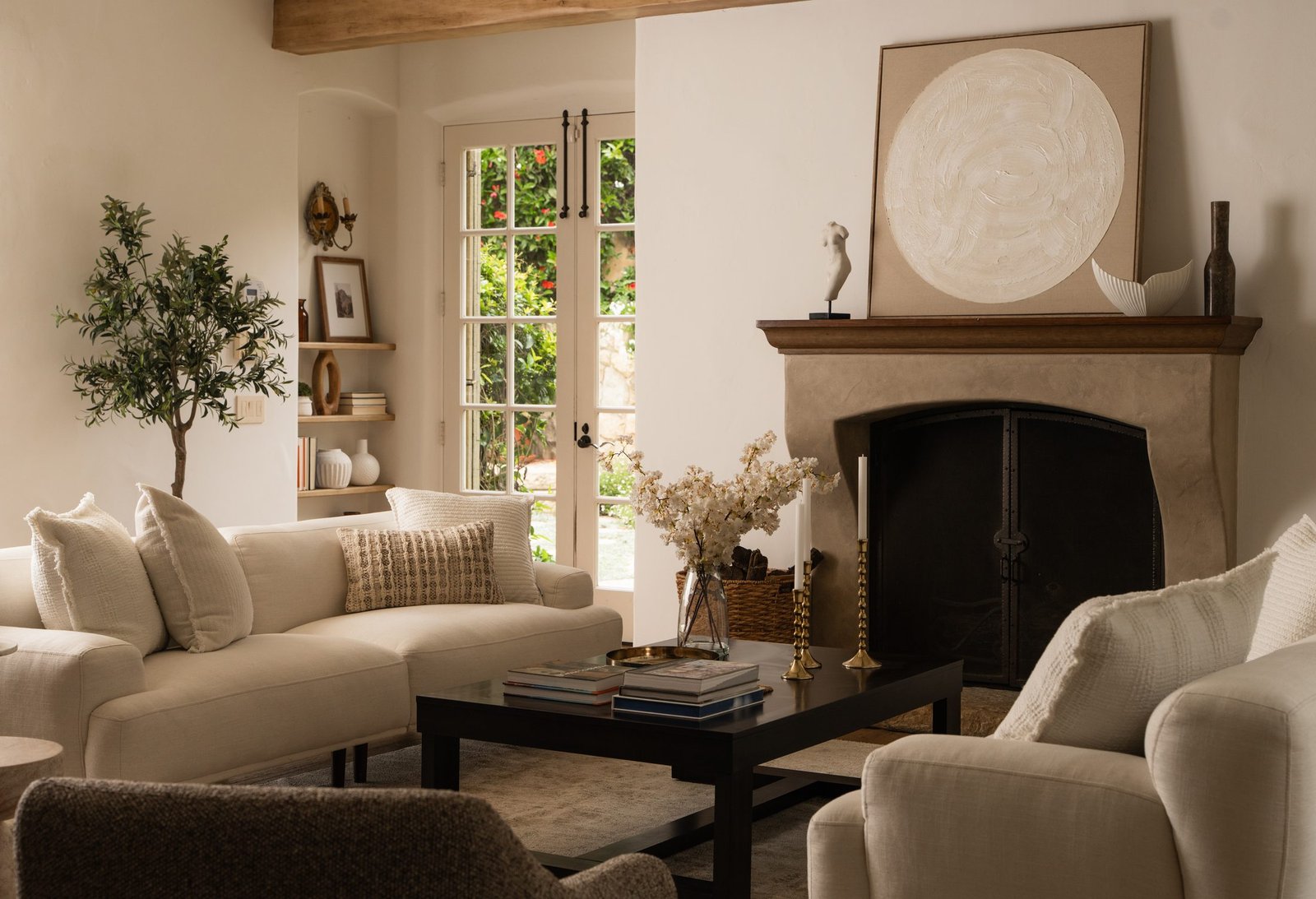Living room with a fireplace, arched openings and soft neutral furnishings by S & S Interiors